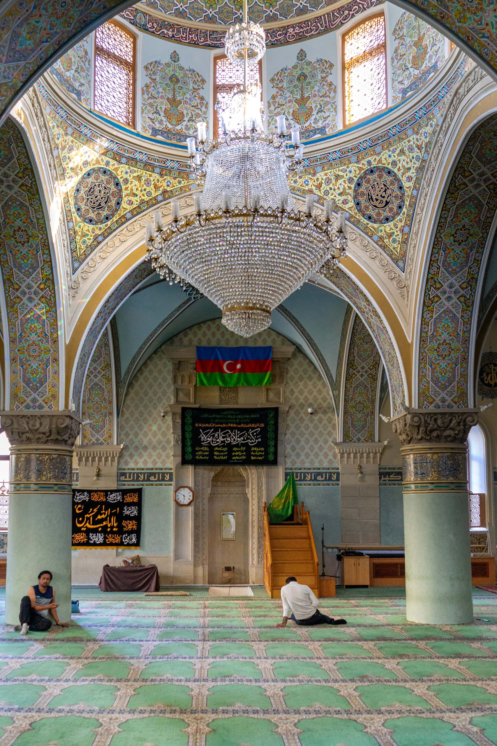 Two men sitting on the green carpet inside a mosque in Baku azerbaijan