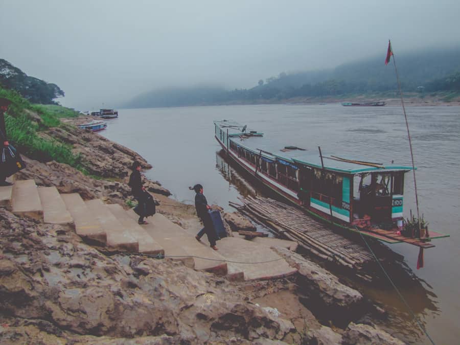 Laos travel photography: Travelers boarding a slow boat on the Mekong river in Luang Prabang, Laos