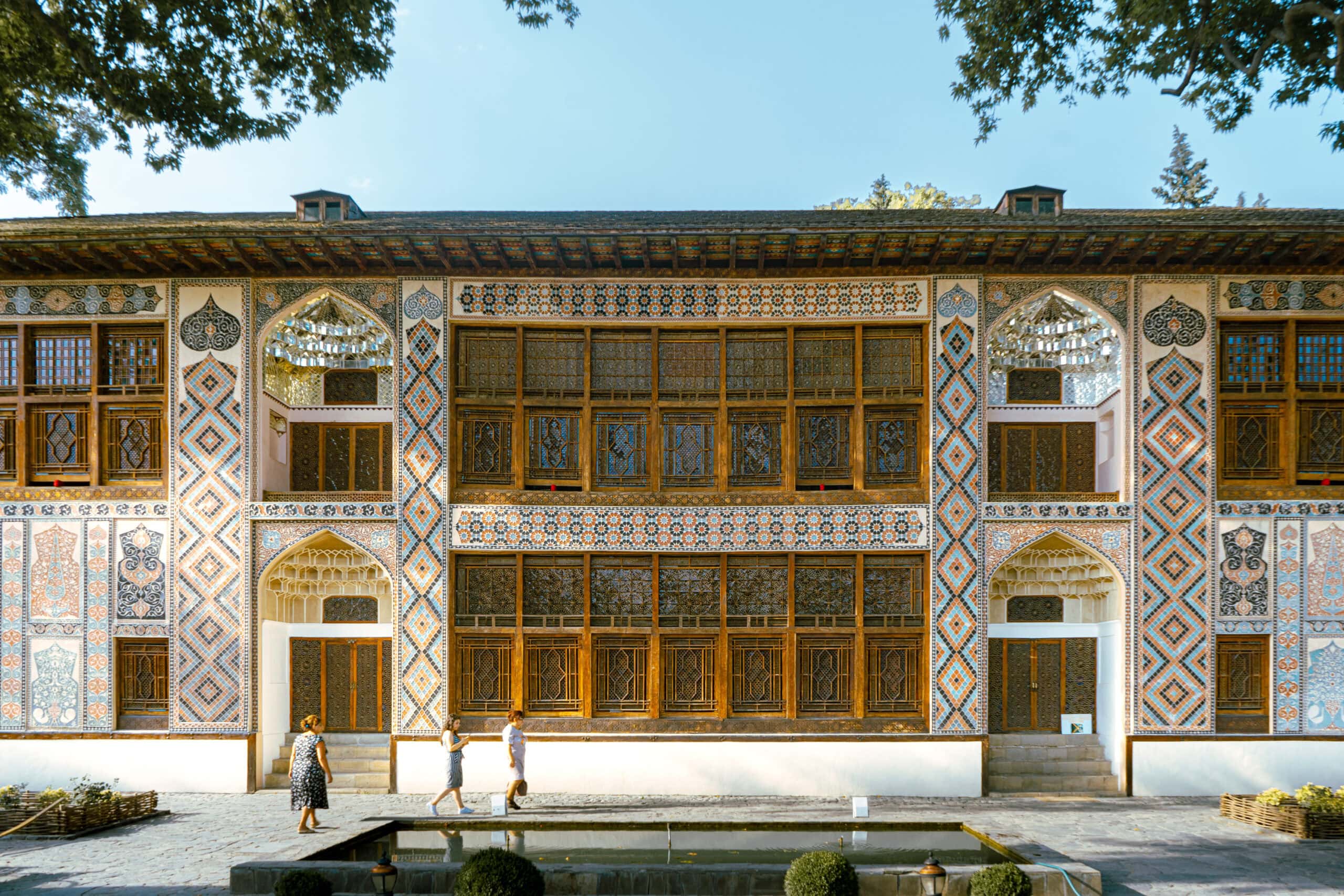 Three women walk in front of the The Shaki Khan Palace in Sheki, Azerbaijan