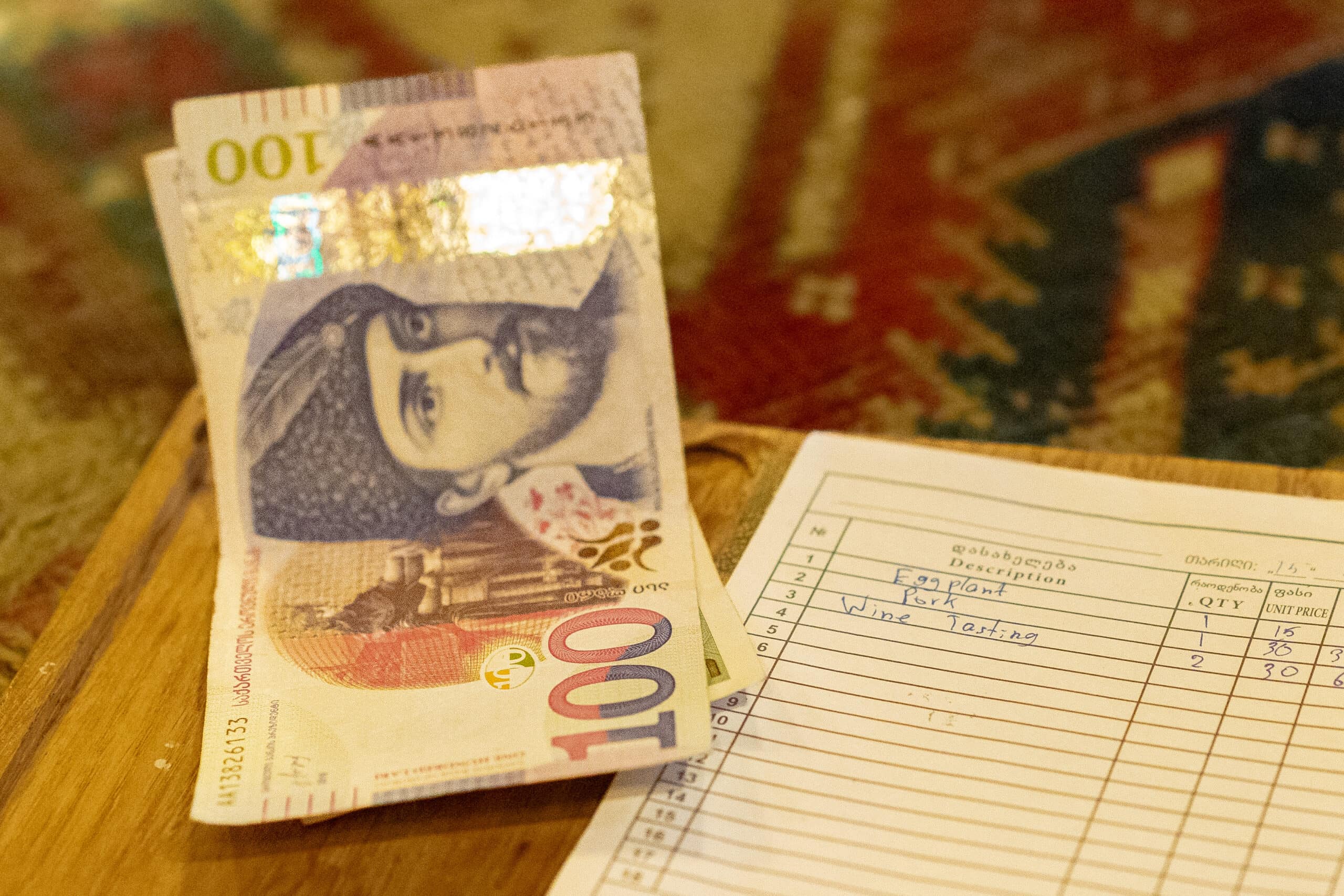 two 100 lari bills next to a bill for lunch
