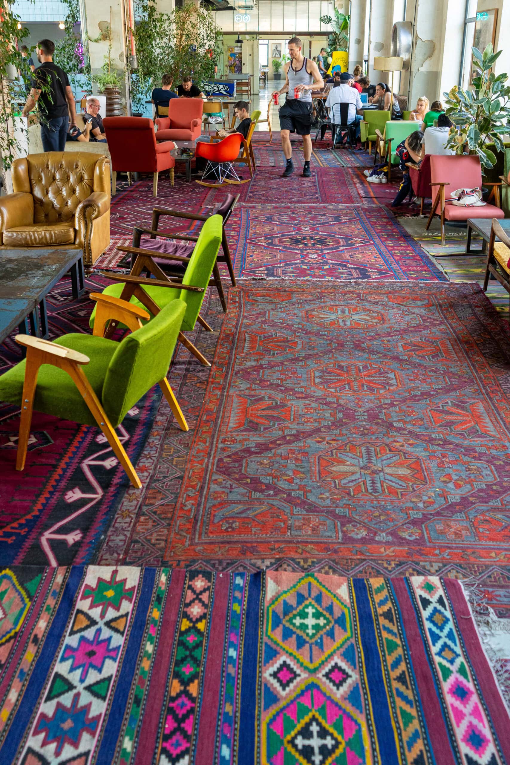 Colourful Caucasus rugs covering the floors of the common spaces at Fabrika hostel in Tbilisi