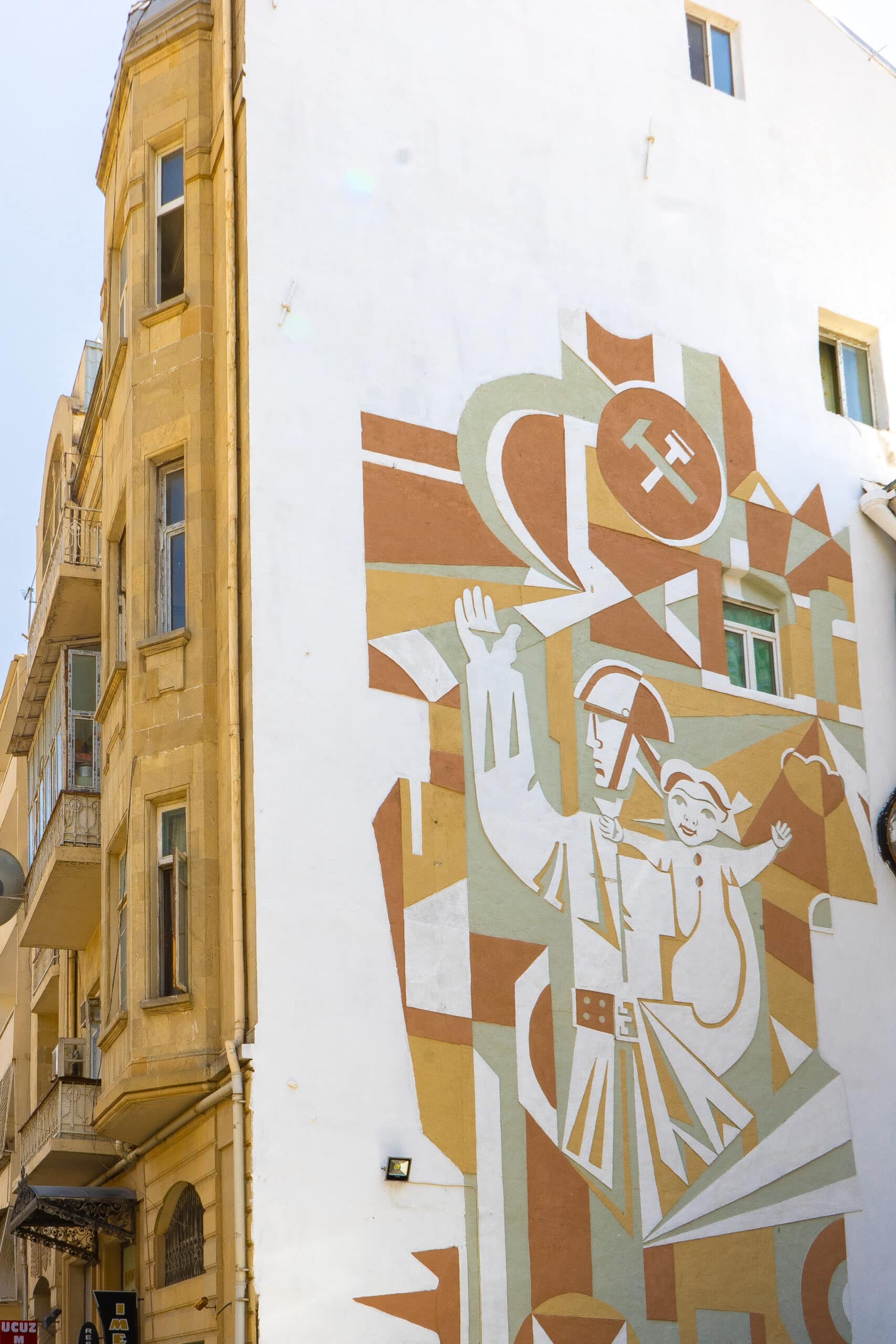 A soviet era mural of a soldier holding a child on the side of a building in Baku, Azerbaijan