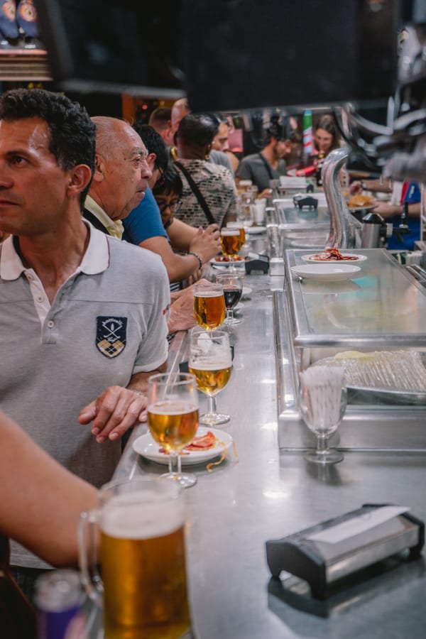 Customers enjoying beer and jamon at a stand up bar in Madrid