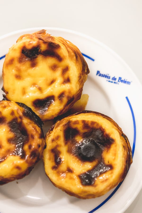 Three egg tarts on a plate from Pasteis de Belem in Lisbon