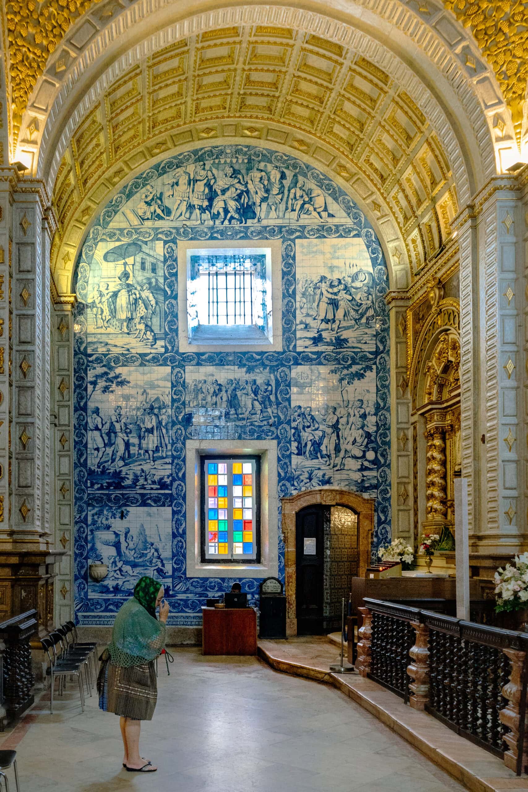 A woman wearing traditional Nazare clothes (7 skirts) prays inside the  Church of Nossa Senhora da Nazaré 