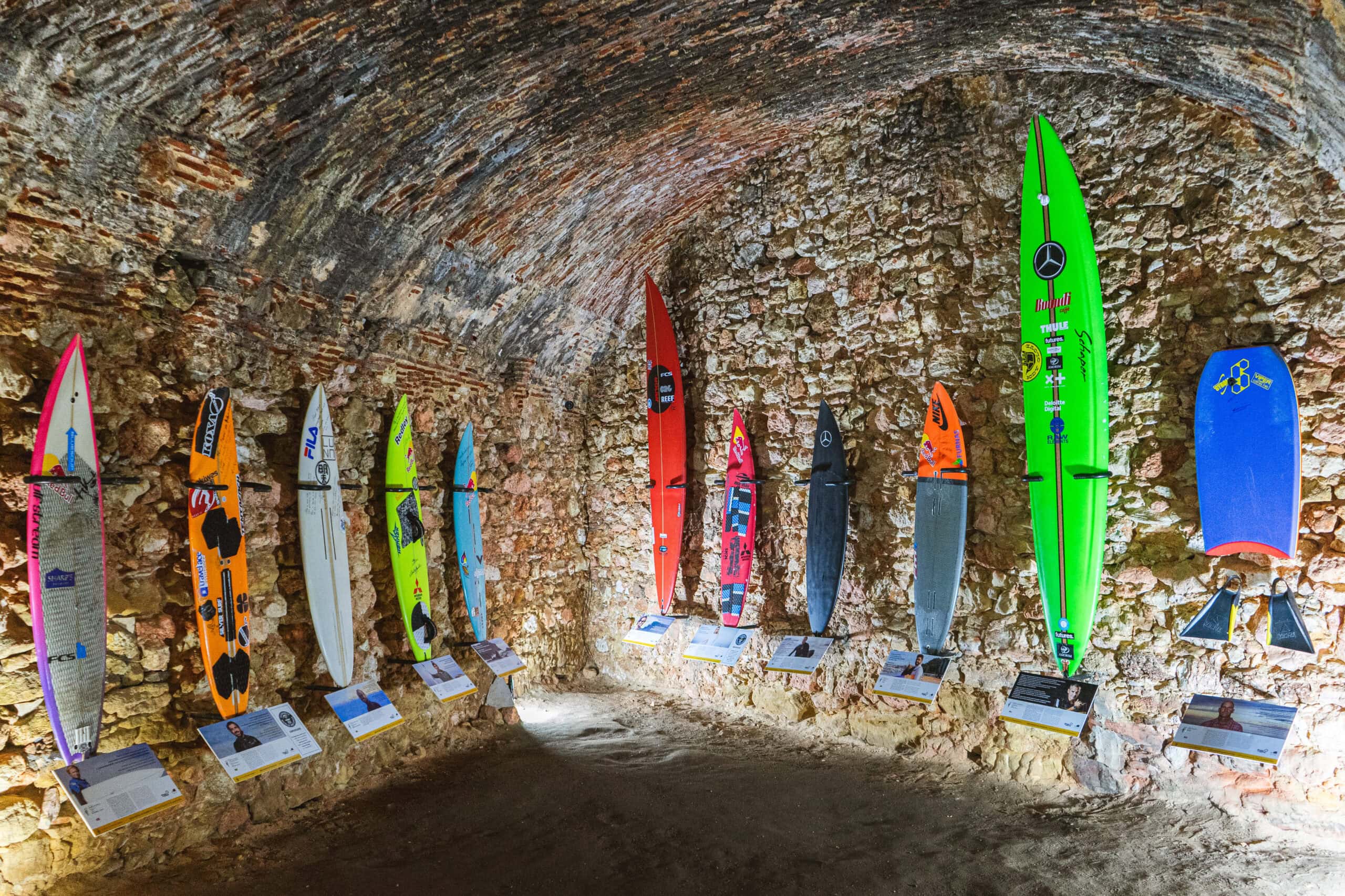Various surf boards on display at the Nazare Surf Museum  inside the Farol da Nazare. Under each surf board is a photo and quotes of the surfer