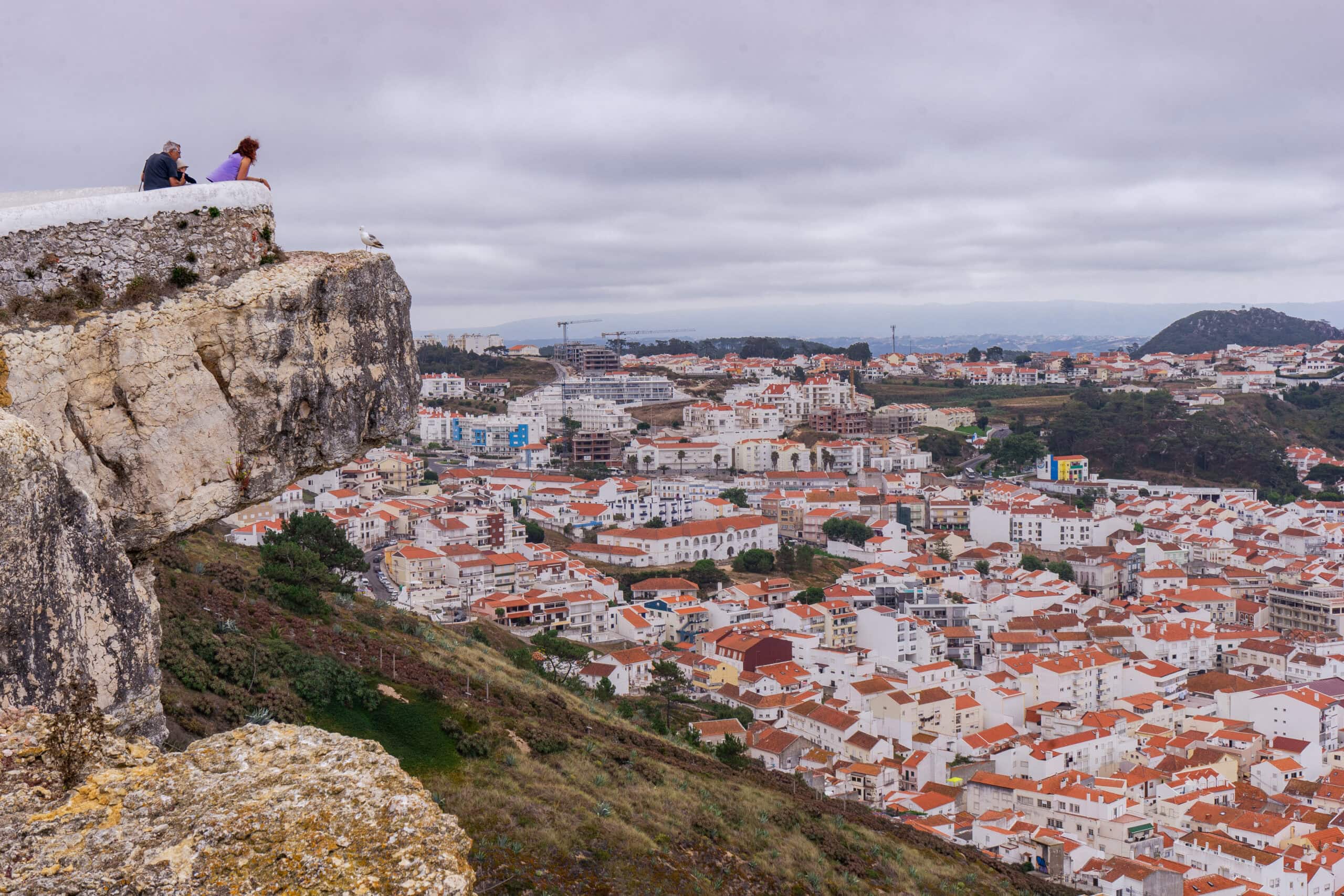A couple peers over the Miradouro do Suberco for a view over Nazare