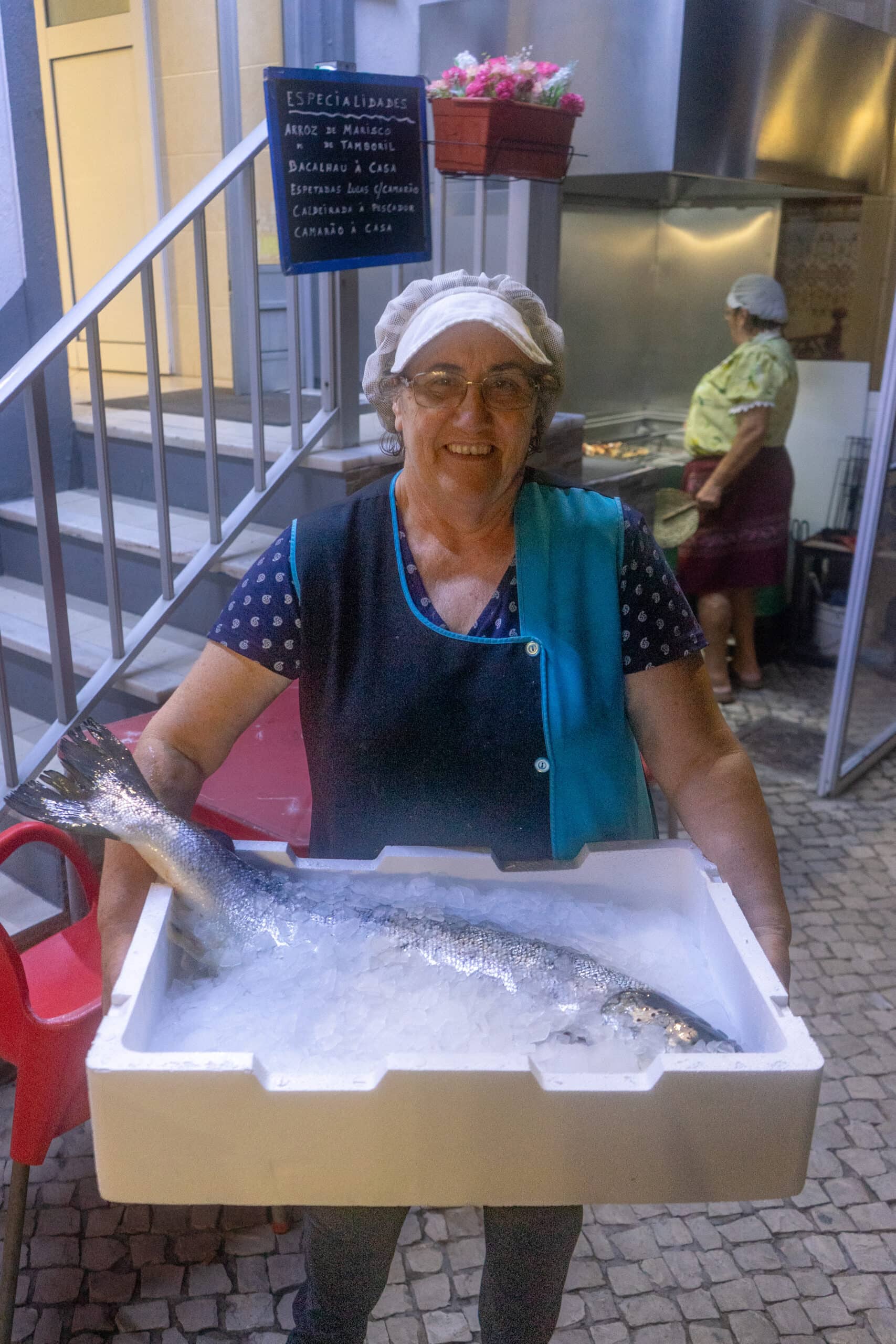 A woman holds a crate with crushed ice and an large Atlantic Salmon at Ole restaurant, Nazare