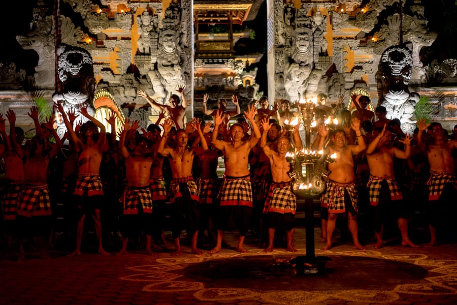 A group of bare chested med dressed in black and white sarongs take part in the Kecak Fire dance in Ubud