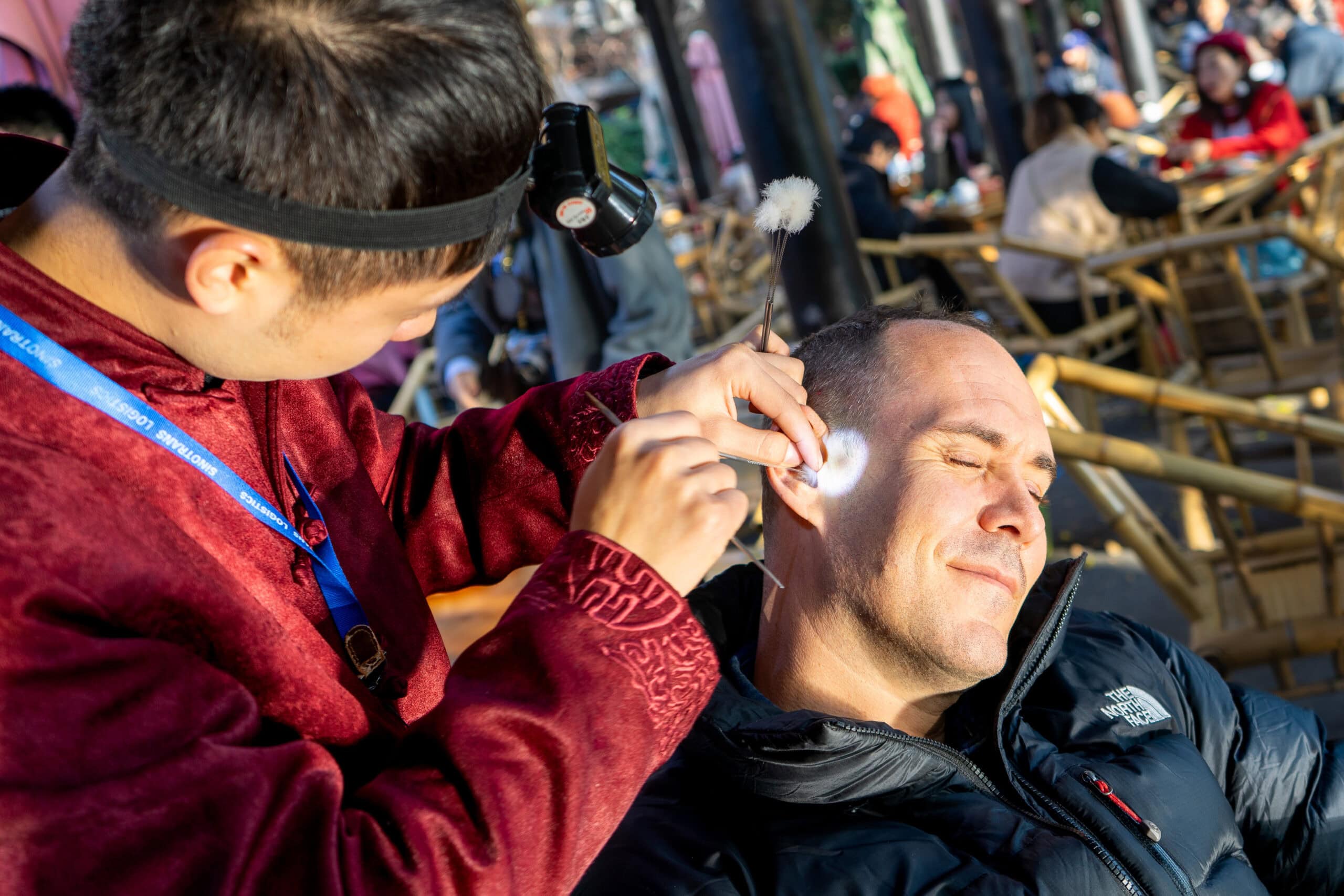 A young man wearing a headlamp cleans my ears with various tools at Heming Tea House in Chengdu, China