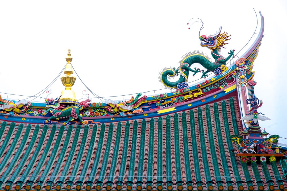 Ornate temple roof at the Nanputuo Temple in Xiamen. It shows a green and yellow dragon sitting on a green tiled roof