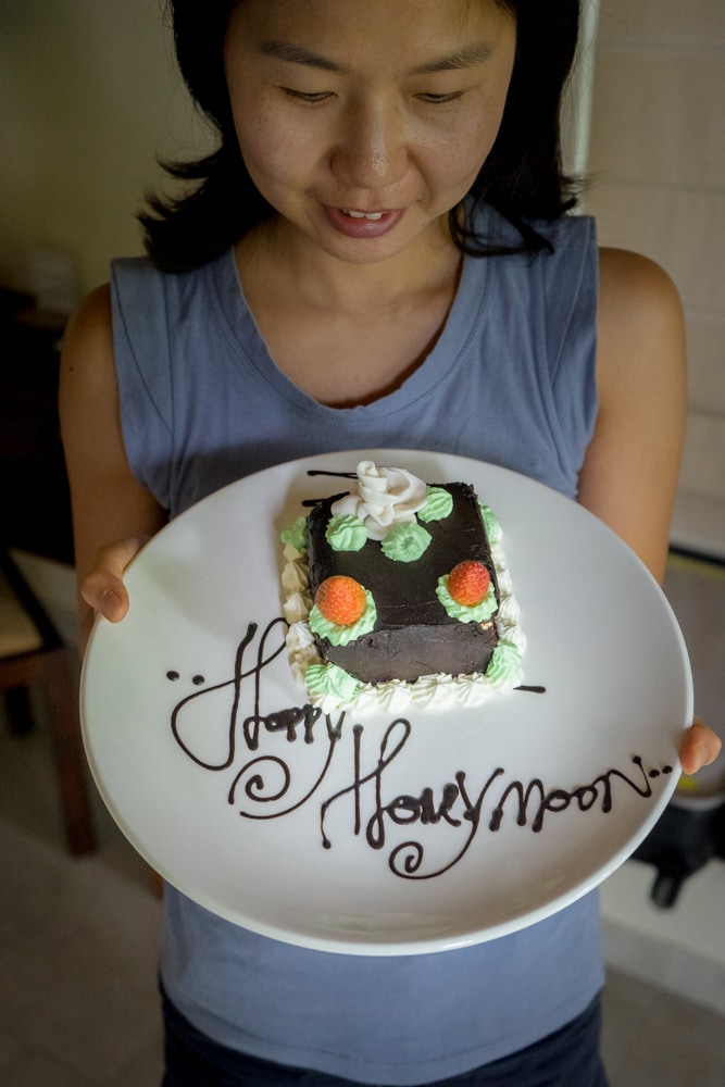 Jin holding a plate with cake and Happy Honeymoon written in chocolate sauce at the Chandi Resort in Lombok