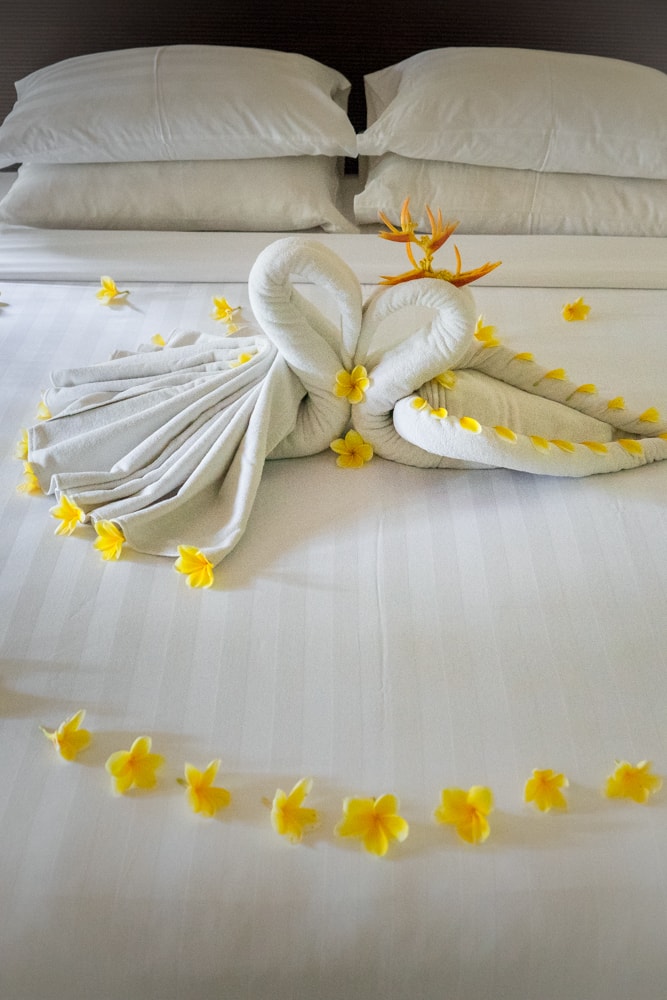 Our bed decorated with folded towels in the shape of swans and frangipani flowers at the Chandi Resort in Senggigi, Lombok