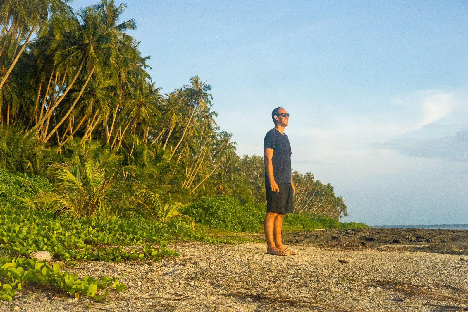 Man standing on an empty beach with palm trees on Asu island