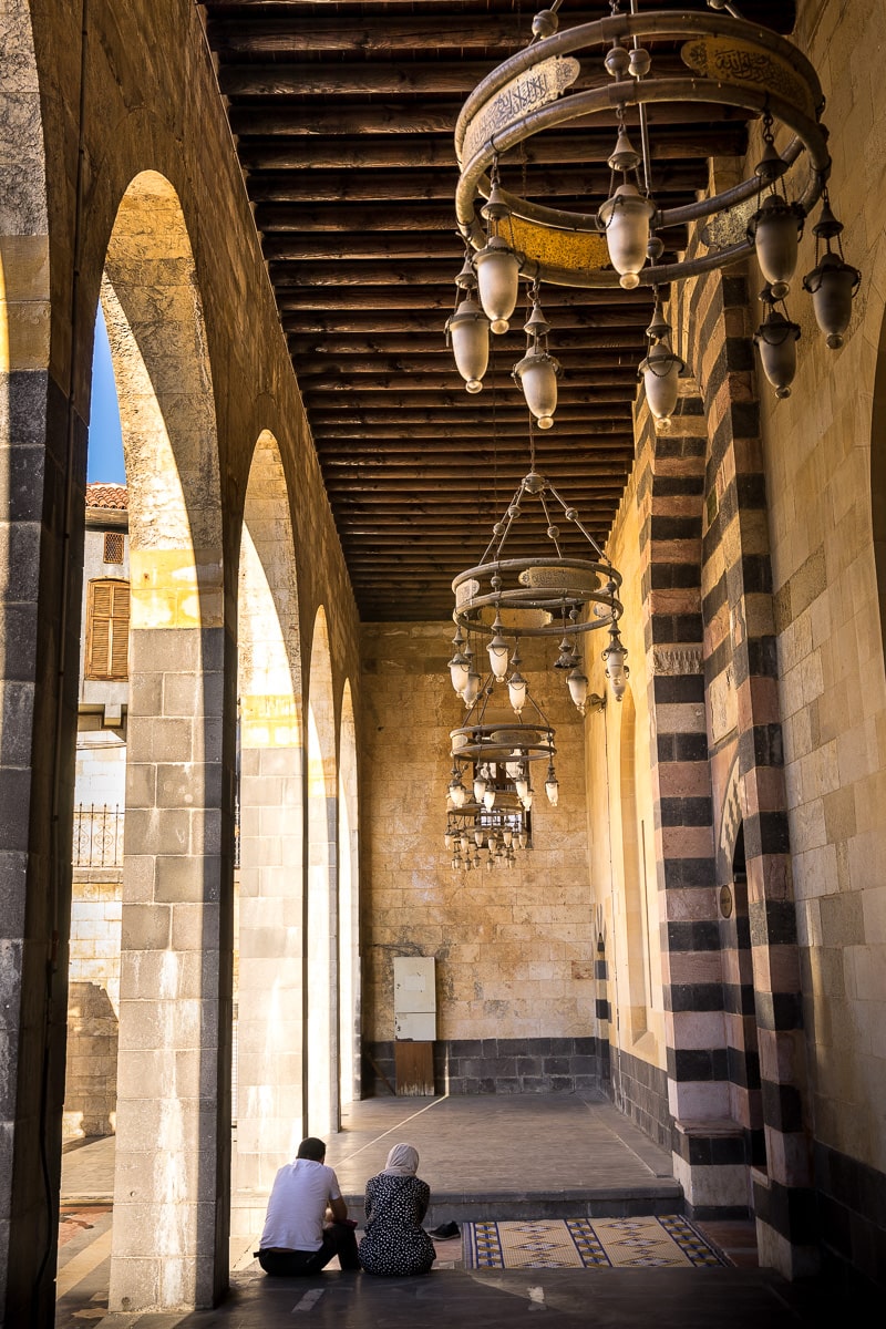 A man and womam sit at the entrance of a mosque in Gaziantep, Türkiye
