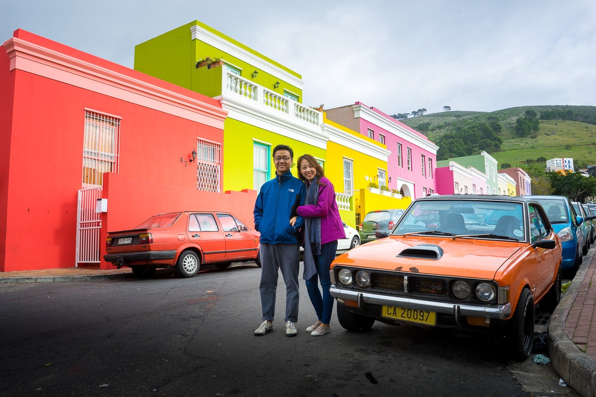 A Korean couple poses for a photo in the Bo-Kaap in front of the colourful houses