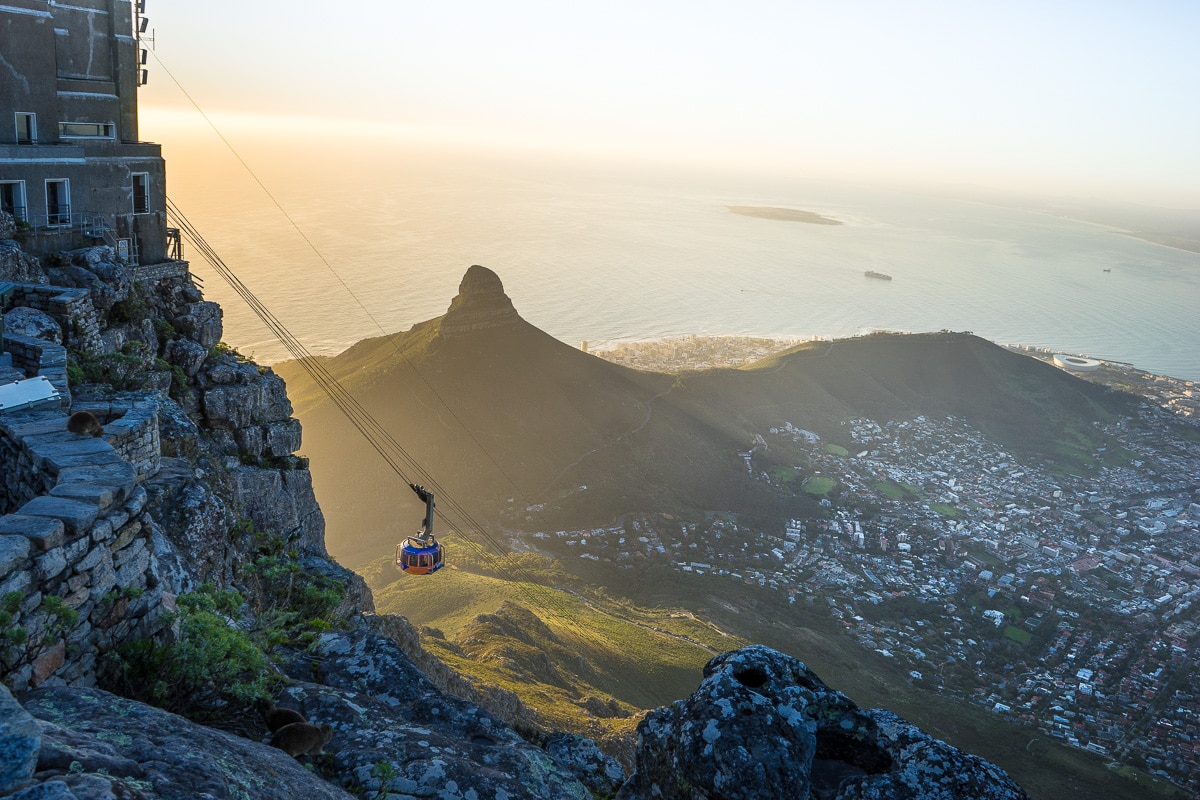 The cable car reaches Table Mountain with Lion's head, the City Bowl and Robben Island in the background