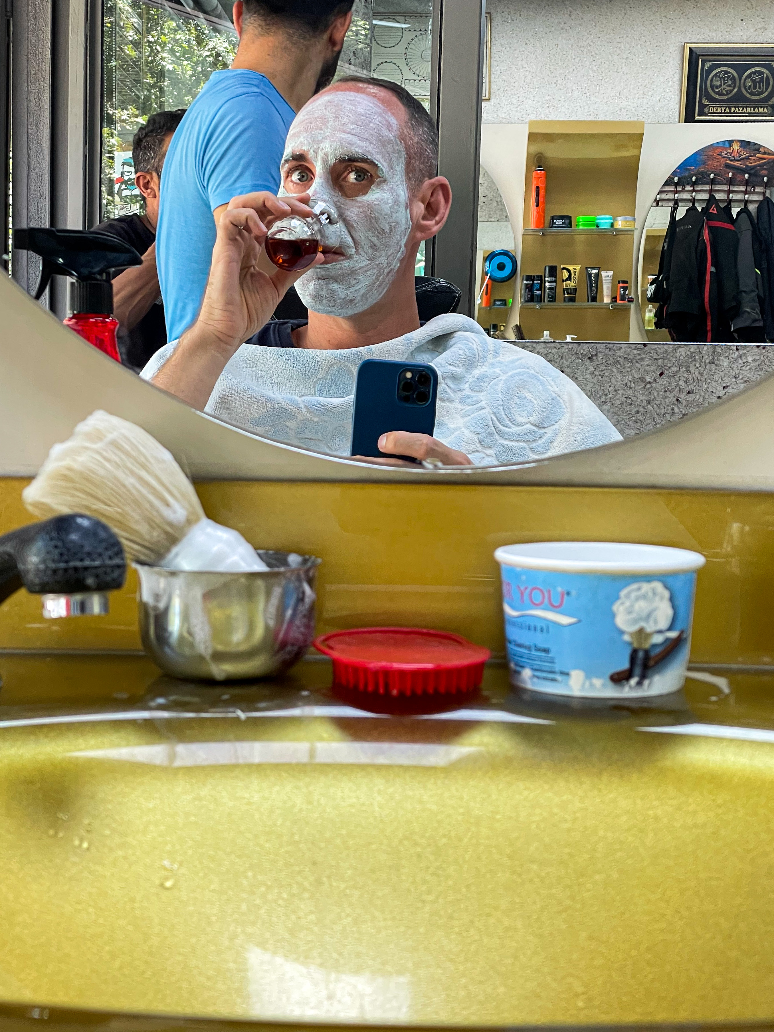 Man drinking tea while getting a face mask at a Turkish barber in Gaziantep