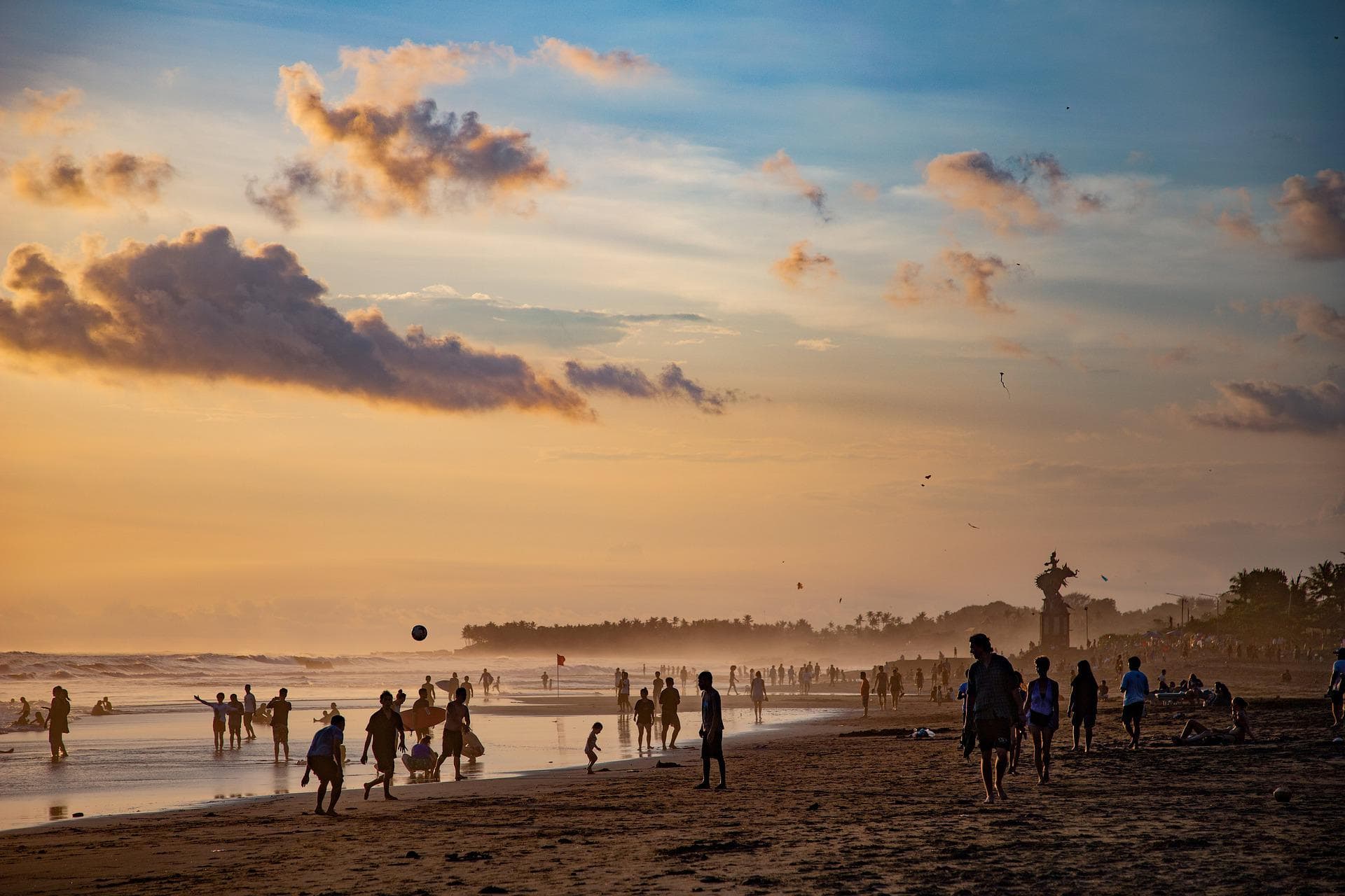 Canggu Beach at sunset, with surfers, families and people talking a stroll
