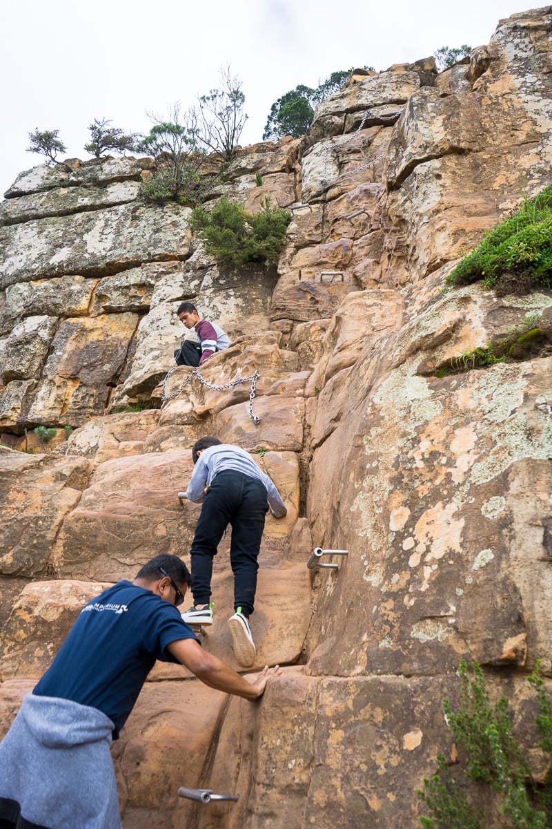 A family climbs up the staples on the Lion's Head Hike in Cape Town