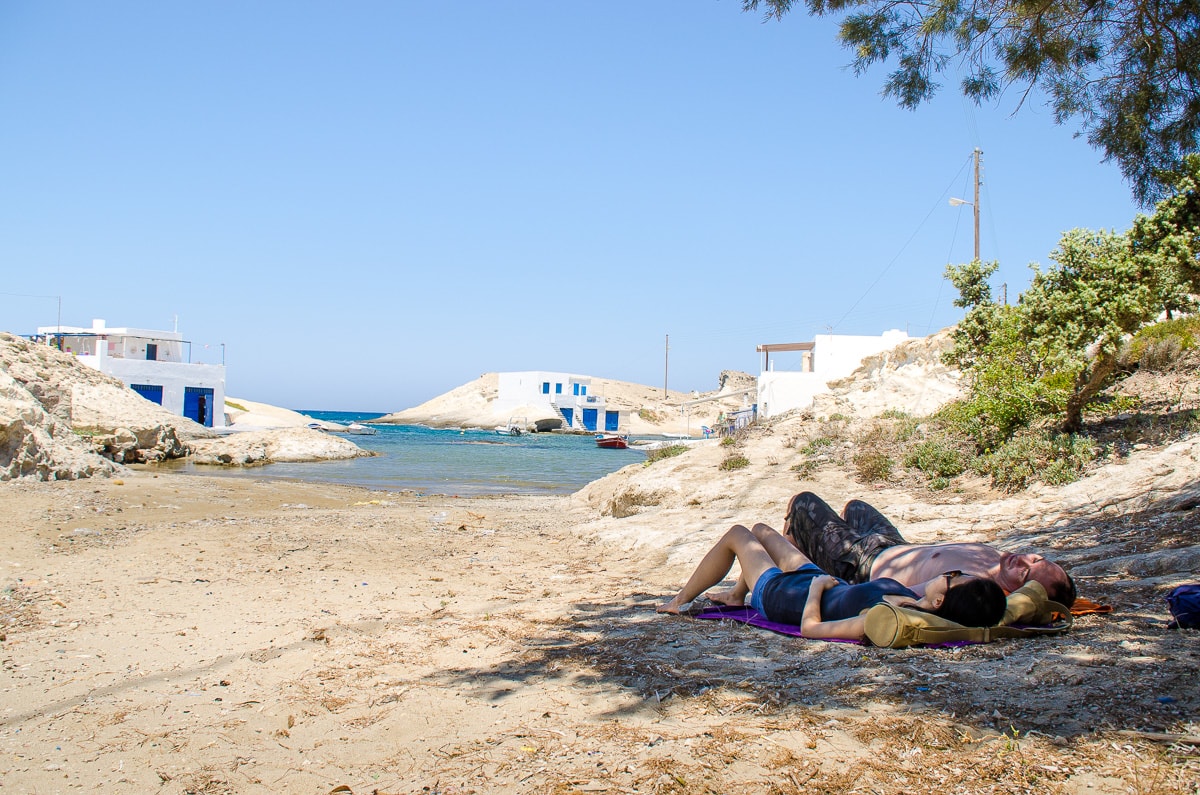 A couple sleeps in the shade of a tree at Agios Konstantinos beach on Milos island, Greece