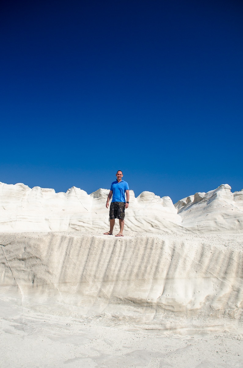 I am standing on the white cliffs of Sarakiniko beach on Milos Island in Greece. The sky is a deep blue in contrast to the white of the cliffs I'm standing on