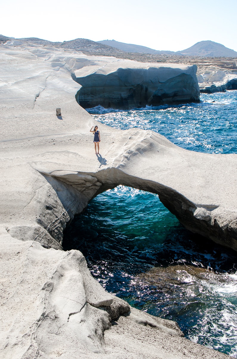 Jin stands on the natural bridge on the Sarakiniko cliffs on Milos island, Greece