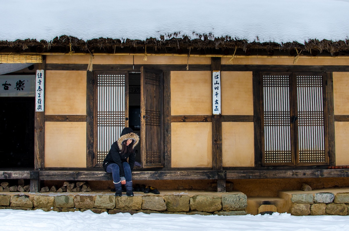 A woman taking off her shoes before entering a traditional Korean house