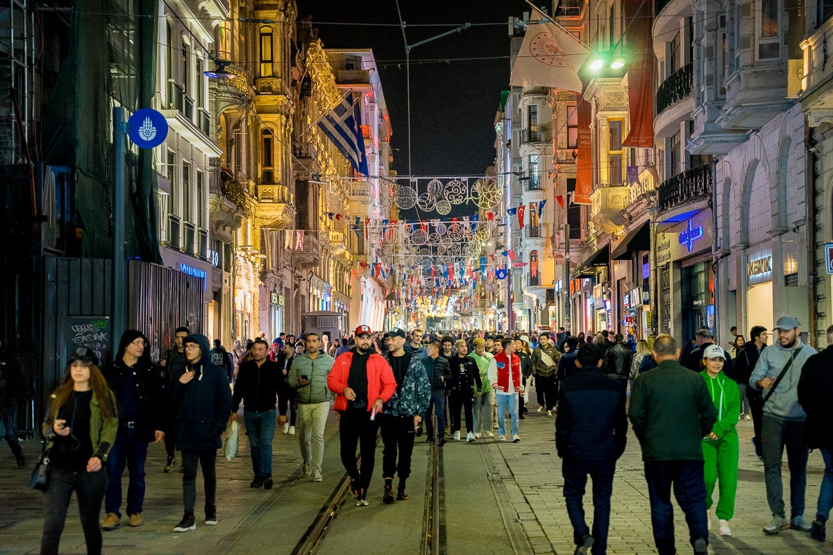 A busy Istiklal Avenue at night. The street is full of pedestrians