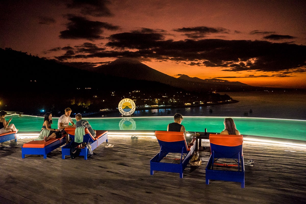 People watching sunset from the deck beside the infinity pool at Sunset Point in Amed