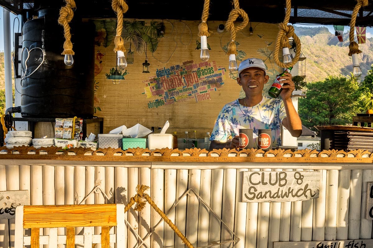 A bar tender serving Bintang Beer from behind a roof top bar in Amed, Bali