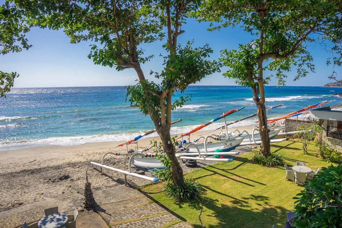 Lawn of Amed Dream Ibus Beach Club right on the beach with traditional fishing boats on the sand