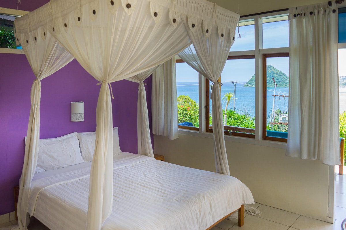 Our double bed room at Golo Hilltop. There is. a mosquito net and white linen. The view through the window is of the islands and the sea