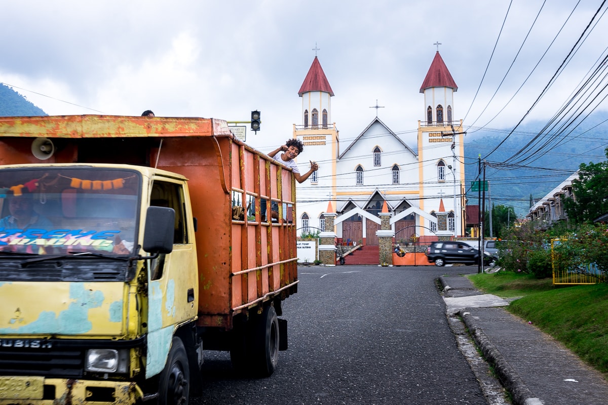 A man waves from a truck as I'm taking a picture of the Ruteng Cathedral