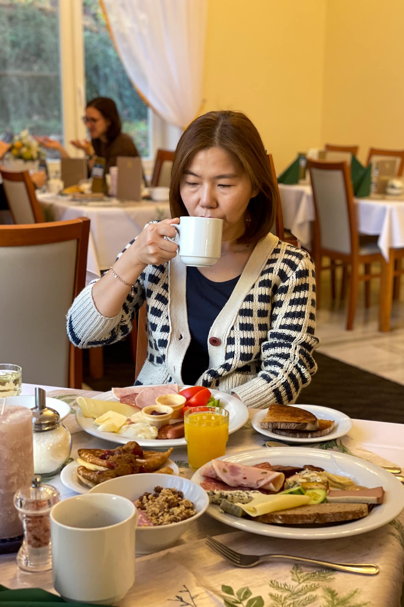Jin takes a sip of her coffee during breakfast