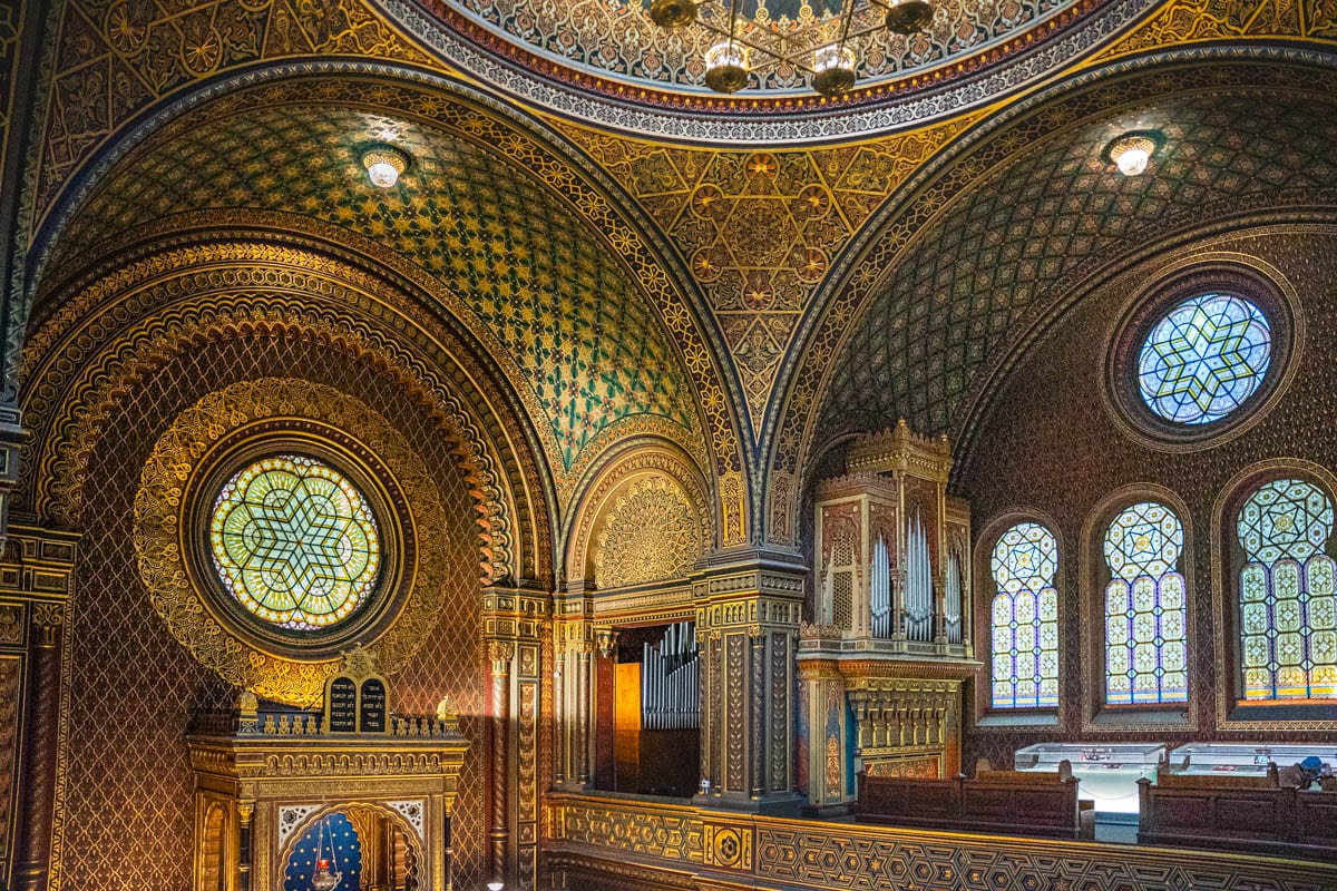 The interior of the Spanish Synagogue. You can see the organ on the balcony, and intricate designs and patterns covering the domes ceiling and walls, with stained glass windows