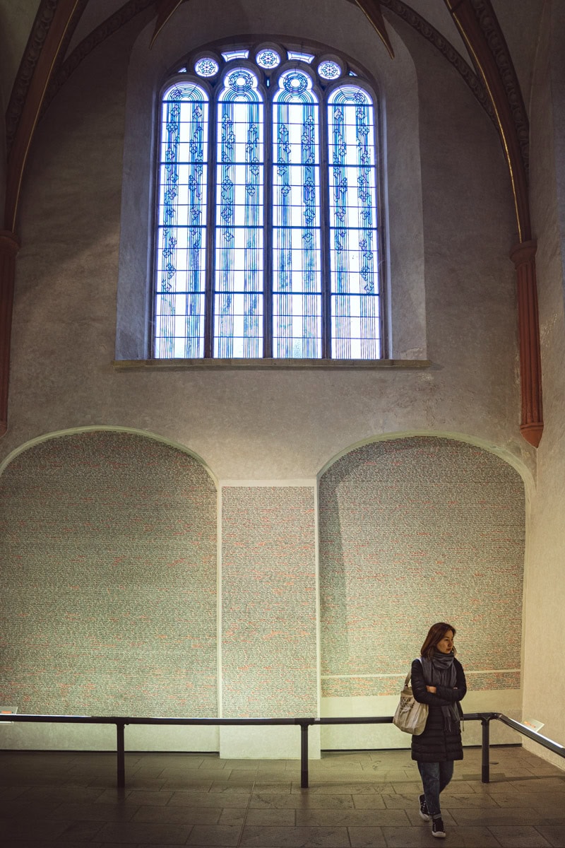 A photo of Jin reading the names on the walls of the Pinkas Synagogue.