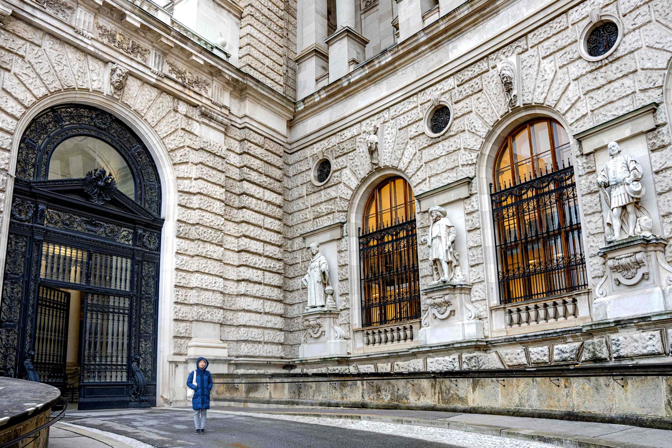 Jin standing in front of a gigantic black door of the Neue Burg, through which we entered the Ephesus Museum in Vienna