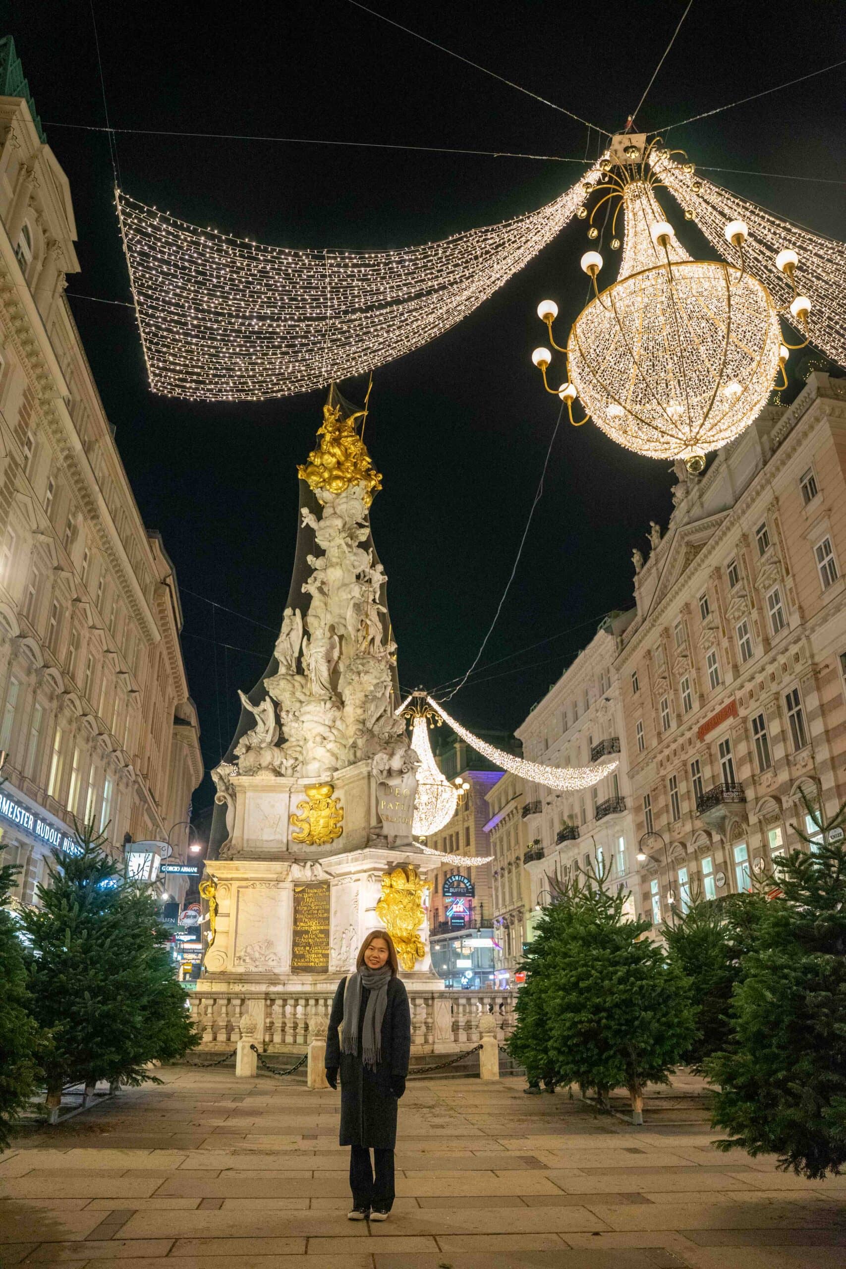 Jin standing in front of the Plague Column (Pestsäule) with the Christmas lights above her on the Graben. The photo was taken during our December trip to Vienna