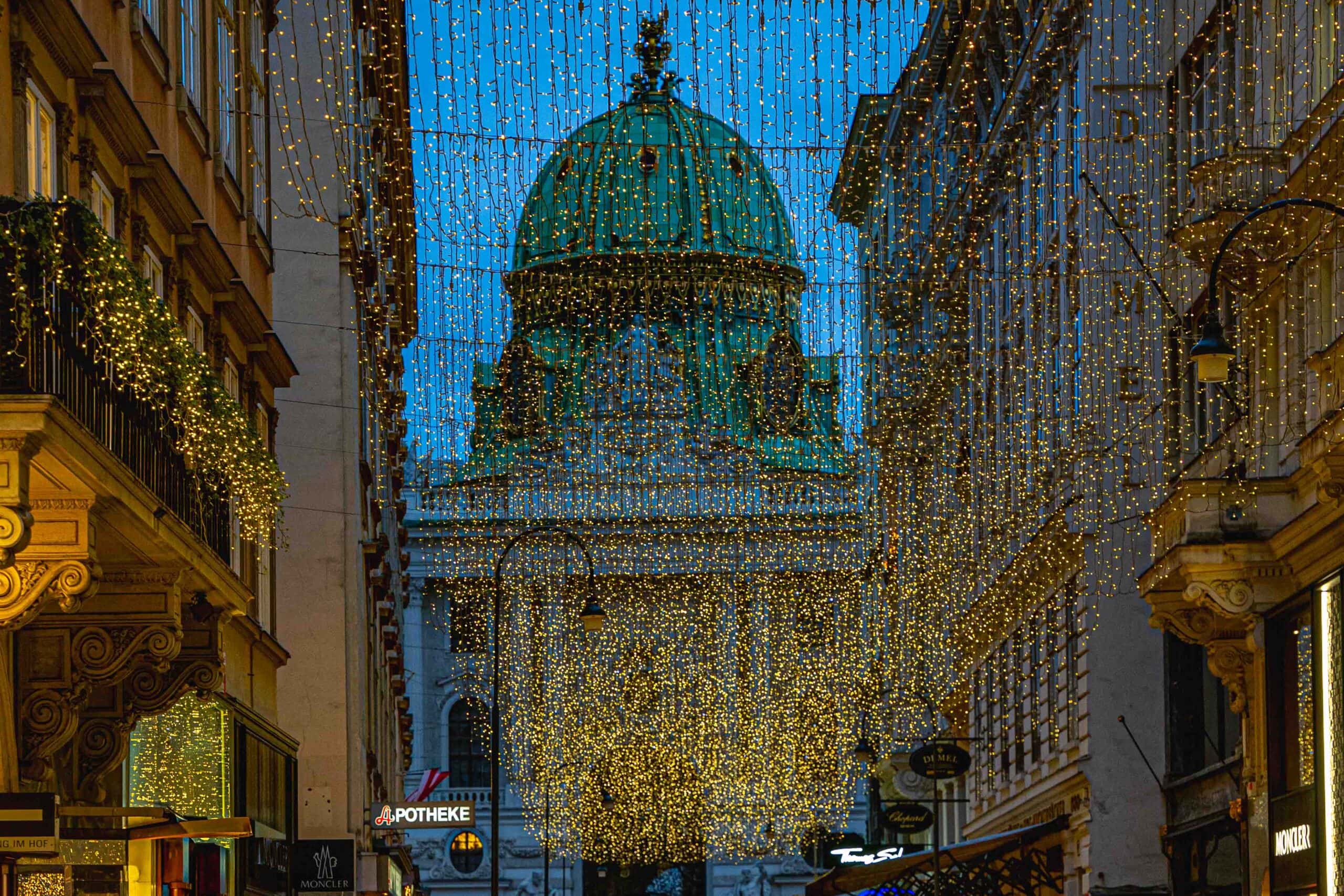Christmas lights on Kohlmarkt with the Hofburg palace behind it