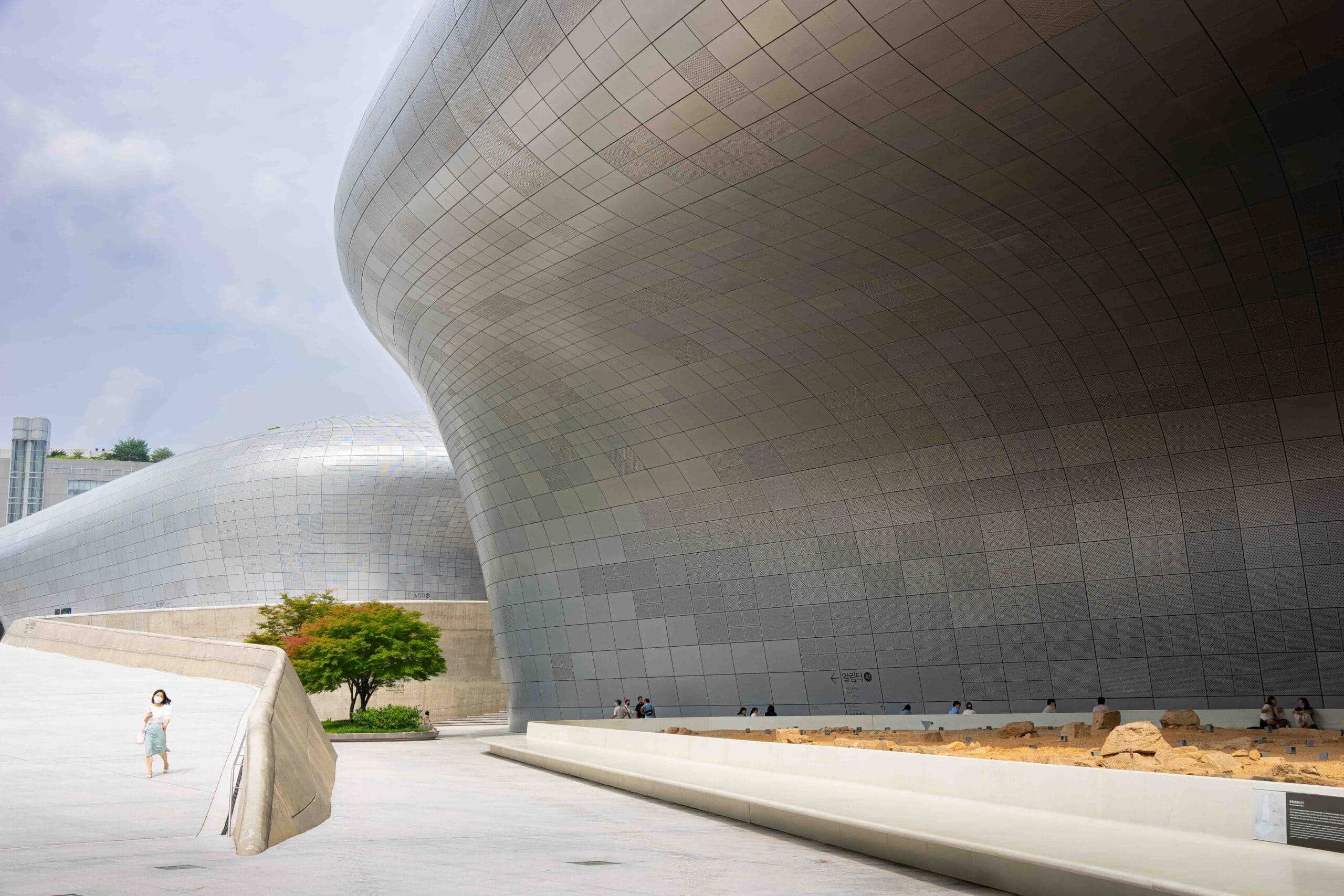Seeing the futuristic architecture of Dongdaemun Design Plaza (DDP) is a top attraction when visiting Dongdaemun. Here you can see a single woman walking under the flowing silver architecture
