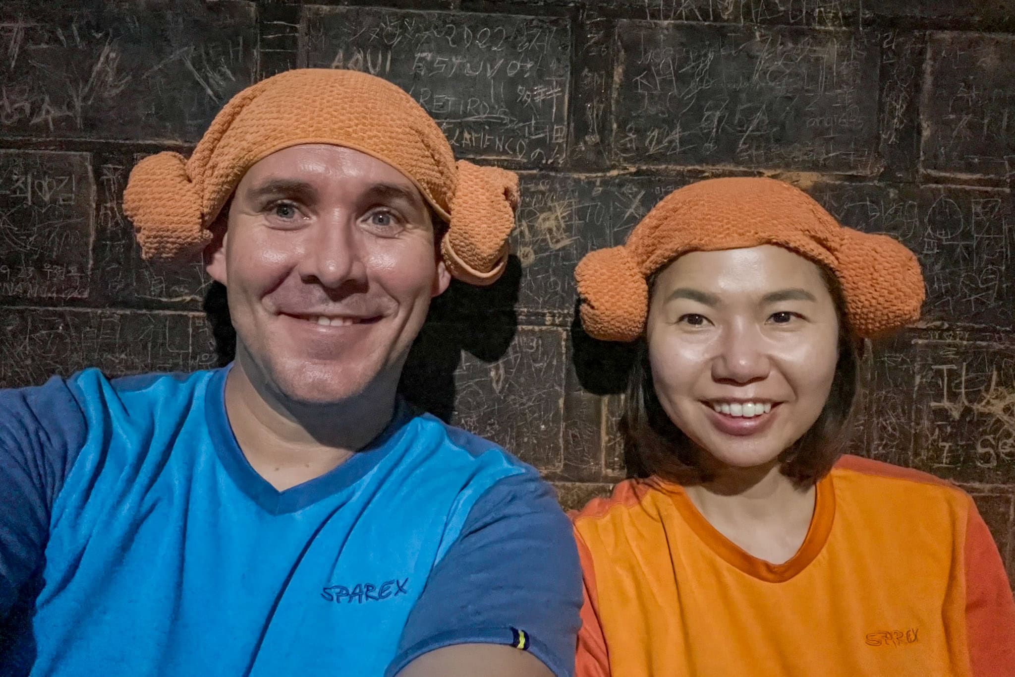 A selfie of us taken inside the dry sauna at Sparex. We are wearing our spa clothes (blue for men and orange for women). We also have the towels folded like ram's horns on our head, which is typical in Korea