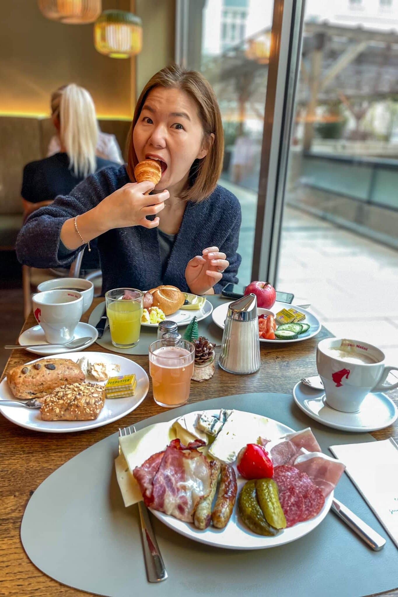Jin is taking a huge bite from. a pastry during breakfast at the Weekend Hotel in Vienna
