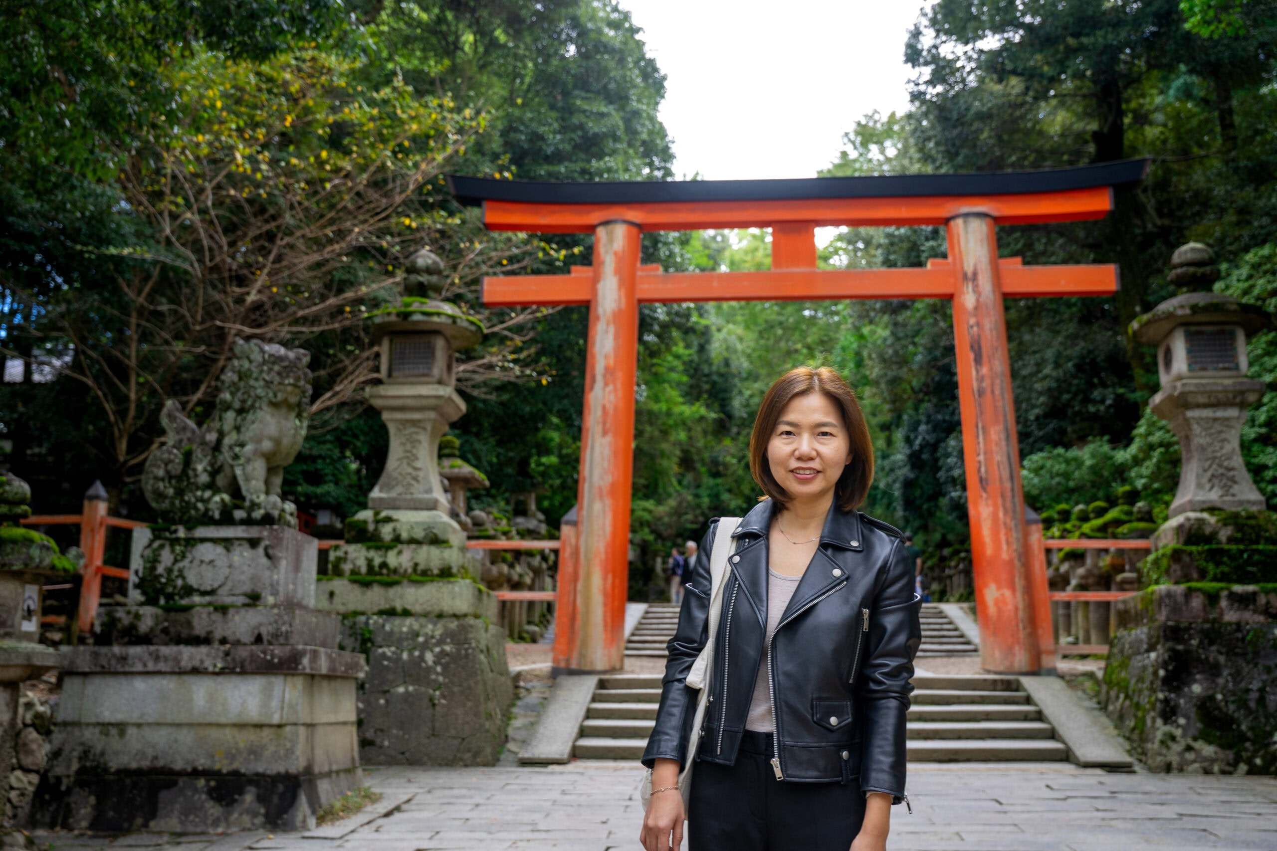 Jin standing in front of a red wooden torii gate at the entrance of the Kasuga Taisha Shrine in Nara, Japan