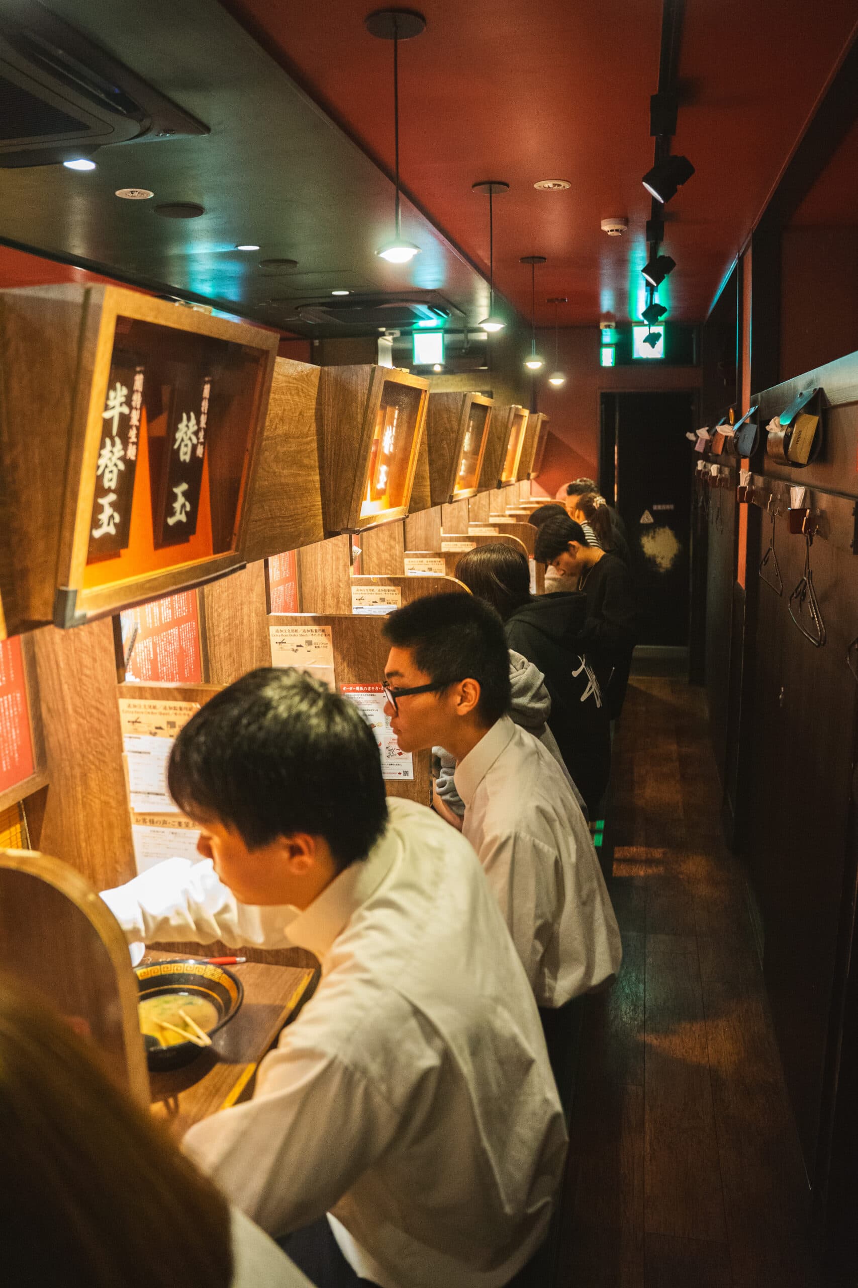 Customers sit in a row eating inside little private cubicles at ICHIRAN Ramen in Hiroshima
