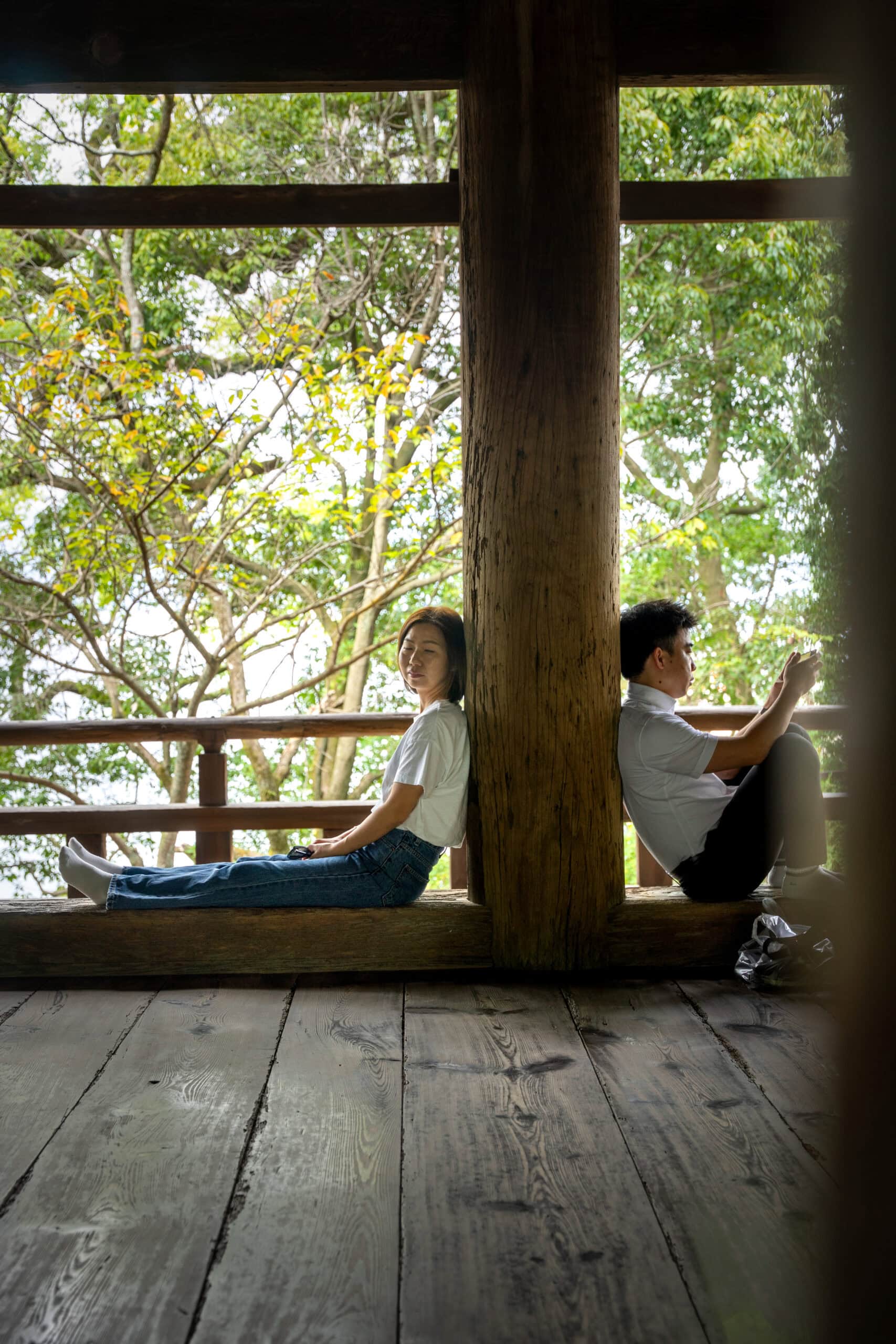 Jin sits with her back against a wooden column inside Senjokaku Shrine