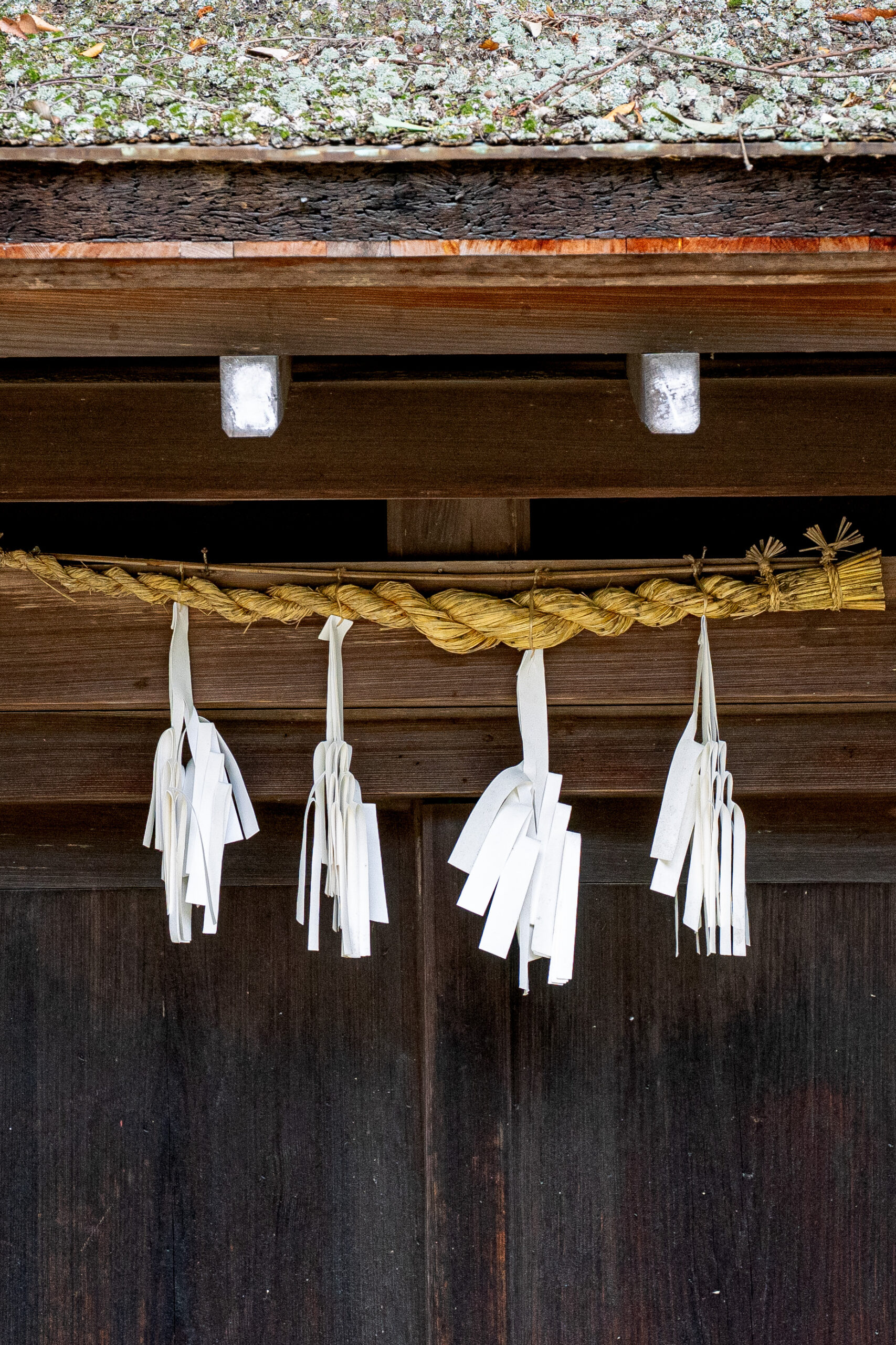 shinto shrine with paper strips hanging against a wooden door on Miyajima Island, seen on our 2 days in Hiroshima
