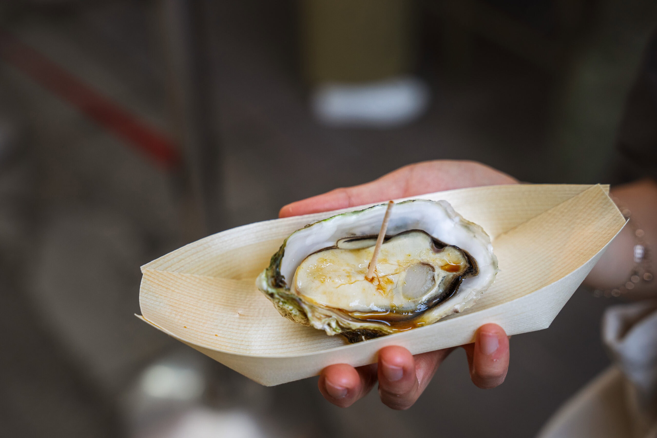 A steamed oyster with soy sauce served inside its shell