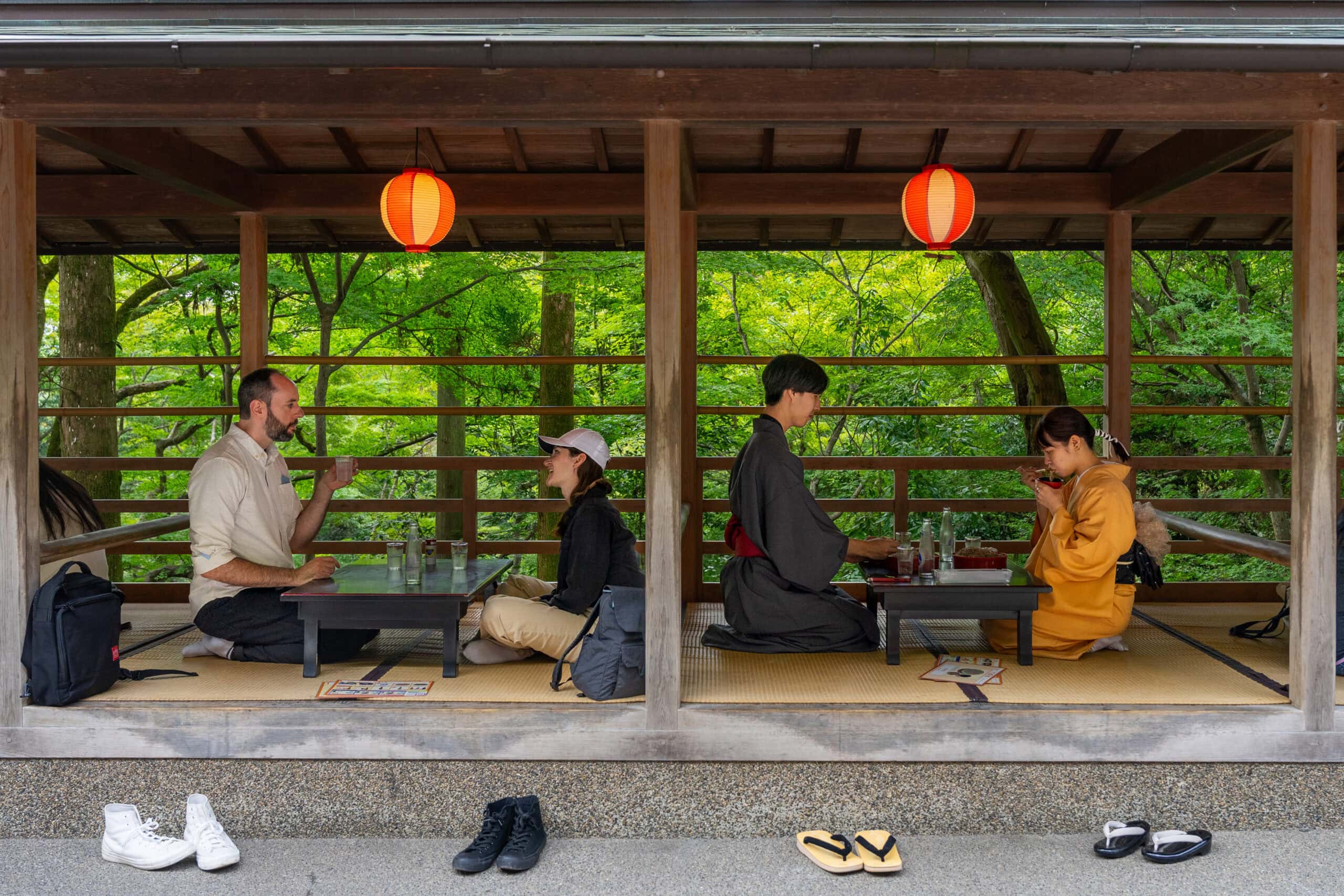 two couples sit on tatami mats eating at low tables with greenery behind them at Takinoya, a small restaurant inside Kiyomizu-dera Temple grounds