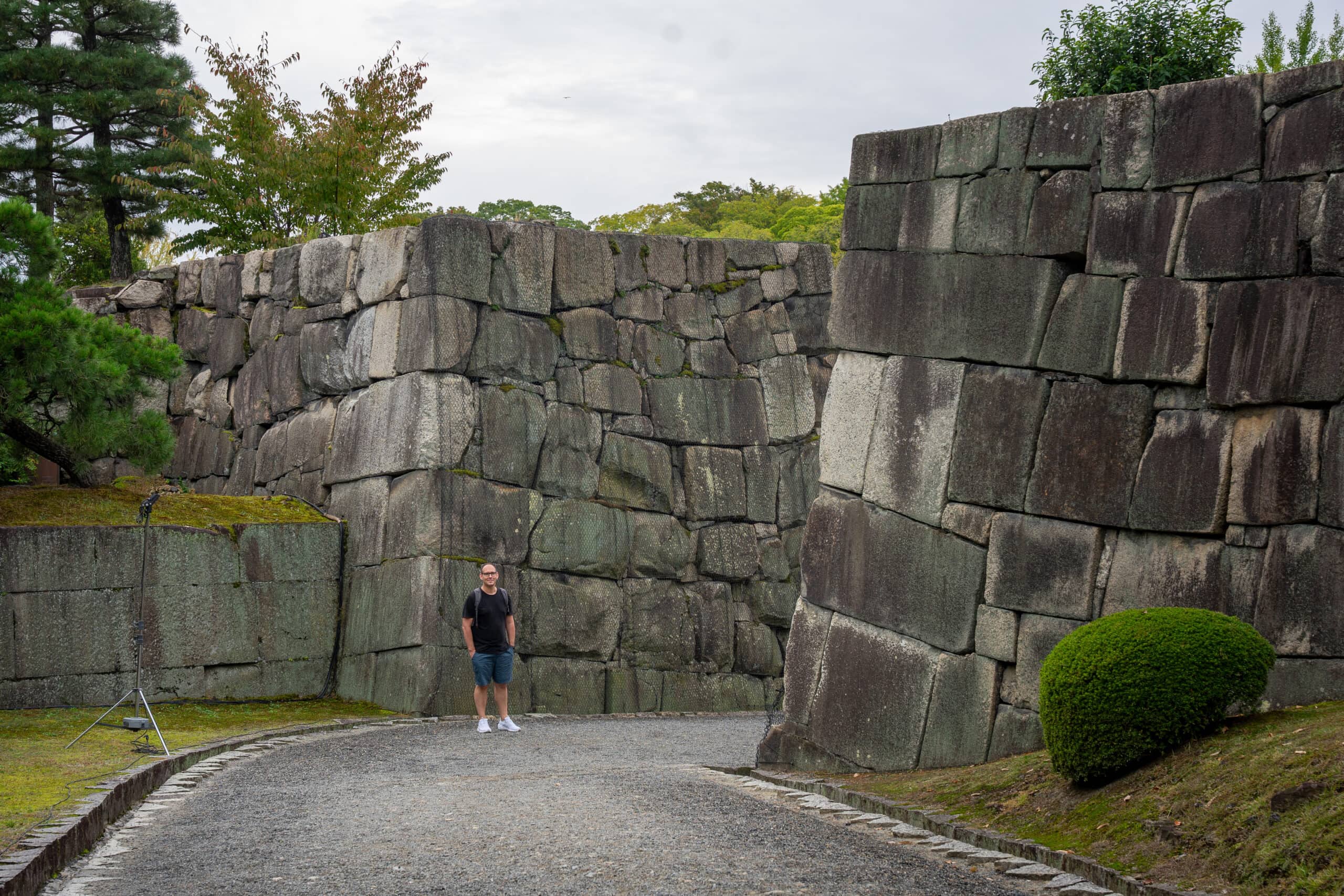 I am standing in front of the large stone walls of the Nijo Castle